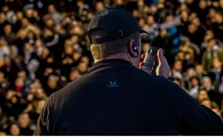 Blu Wing guard with a radio watching a crowd
