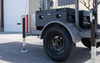 Close-up of a surveillance trailer's wheel, jacks and equipment box